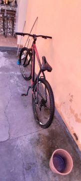 Bicicleta vermelha e preta ela é usada 