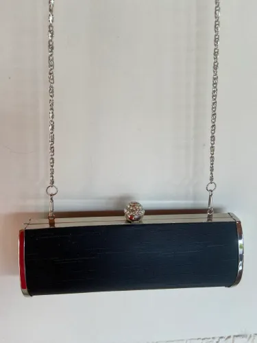 Bolsa Cluth, preta e prateada com pedraria no fecho, de mão e ombro 