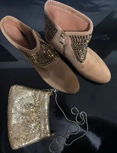 Vende se um par botas de lantejoulas com uma bolsinha de lado.