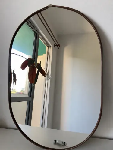 Espelho oval decorativo com acabamento em corino marrom costurado