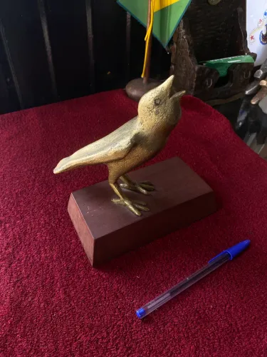 Escultura de pássaro em metal com base em madeira
