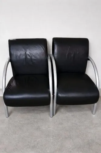 poltrona decorativa de recepção com revestimento sintético preto e braços de alumínio. 