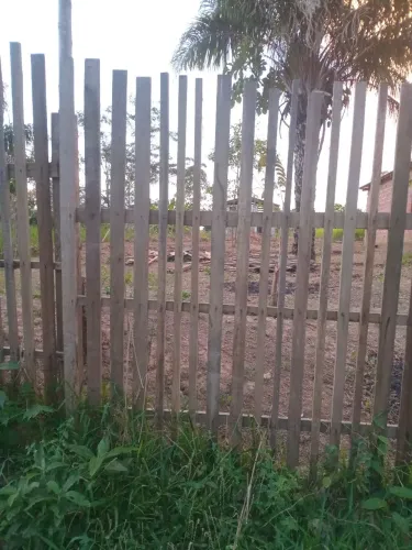 Terreno com casa de madeira inacabada.