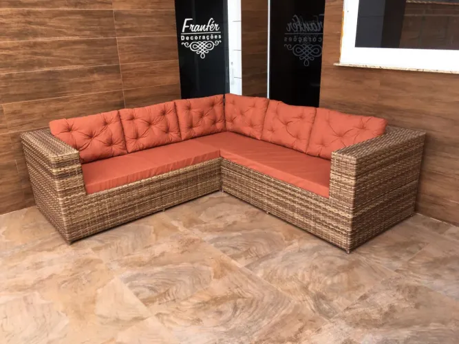 Sofá em L de vime com almofadas terracota. Estrutura em alúminio