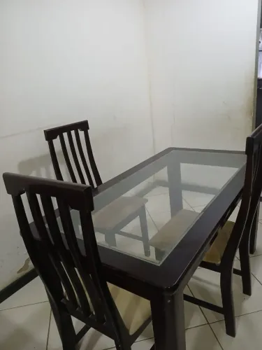 Mesa de madeira com vidro em cima e três cadeiras