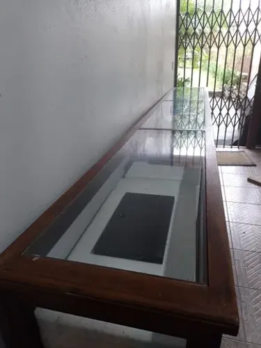 Balcão vitrine em madeira e vidros frontal/lateral/base superior.