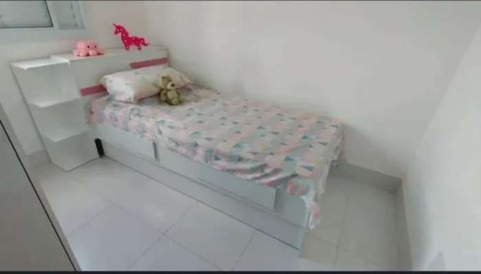 Cama solteiro com cama auxiliar, baú, gavetas e prateleiras decorativas.