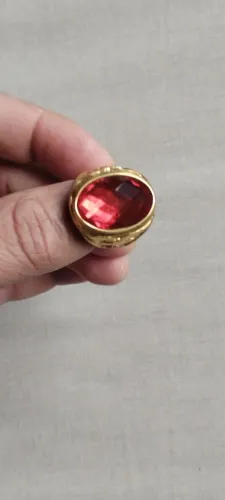 Anel com pedra vermelha, com o símbolo se águia, do lado direito e do lado esquerdo.
