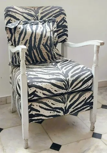 Antiga cadeira braços madeira patinada branca. Encosto e assento estofados tecido zebrado
