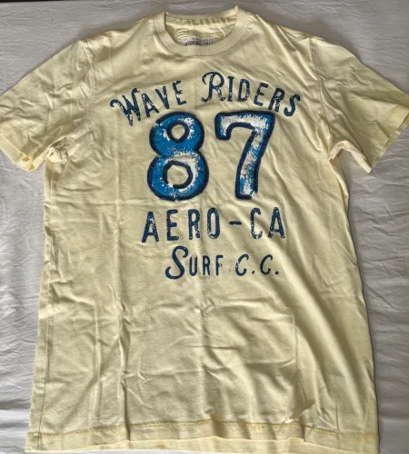 camiseta amarela da Aéropostale com estampa frontal "Wave Riders 87 Aero-CA Surf"