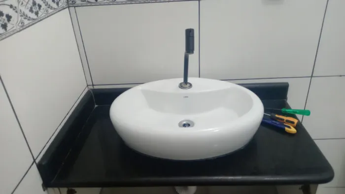 Bancada de granito preto com pia pra banheiro.