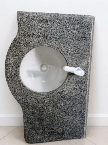 Bancada de banheiro em granito cinza com cuba de louça embutida, torneira branca instalada