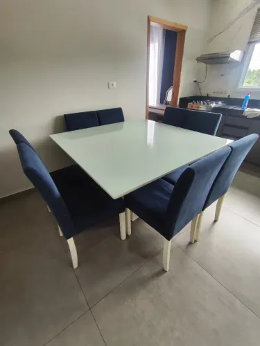 Mesa de madeira maciça, laca branca, 1.40 por 1.40, oito cadeiras azuis.