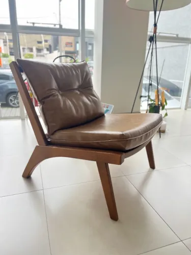 Cadeira com a estrutura em madeira e estofado revestido em couro. Produto com design