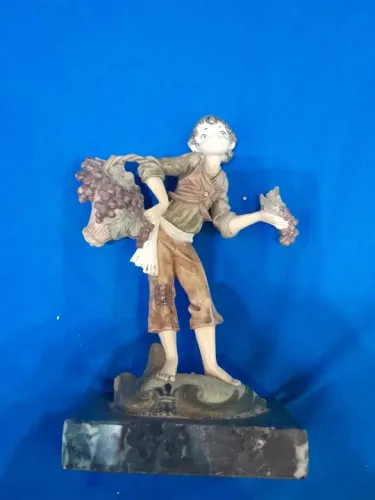 Estatueta de menino com uvas
