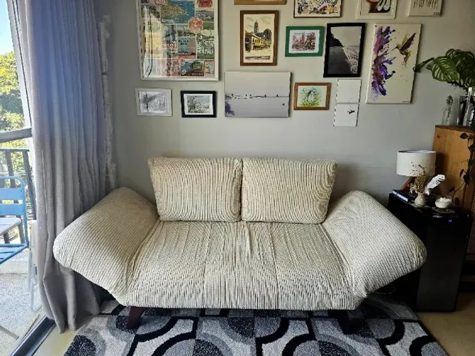 Sofá-cama compacto com braços reclináveis e pés de madeira