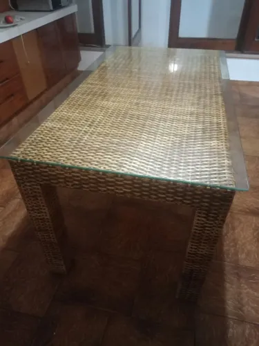 Mesa em alumínio revestida com palha plástica e tampão de vidro sem cadeiras.