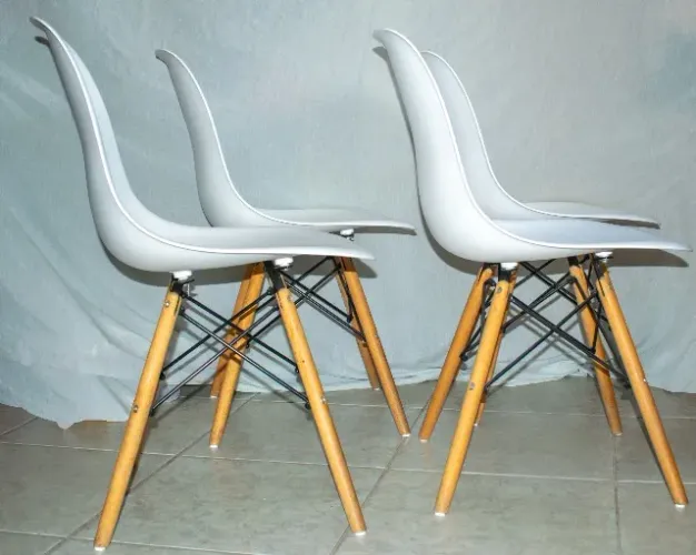 4 cadeiras de jantar Eames estilo Eiffel, com assento branco e pés de madeira.