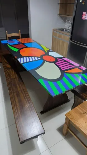 Mesa de madeira com tampo de vidro e com bancos para área de festa