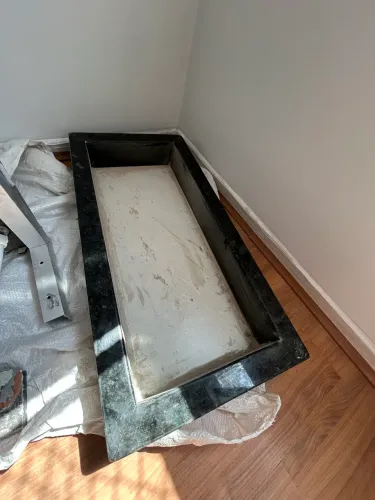 Nicho de mármore verde Ubatuba com borda em meia esquadria e fundo em porcelanato cinza.