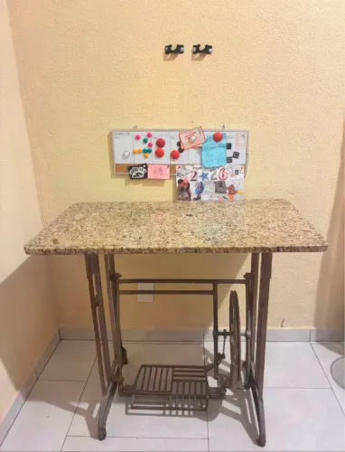Mesa de máquina de costura antiga, pés de ferro e tampo de mármore.
