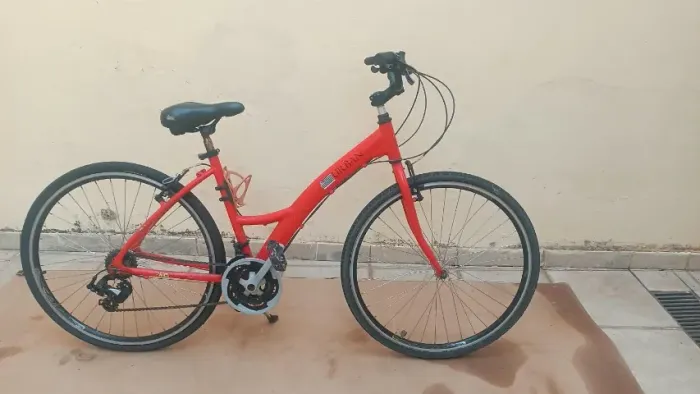 Bicicleta urbana laranja, semelhante ao modelo da Tito Urban aro 700 com 21 marchas.