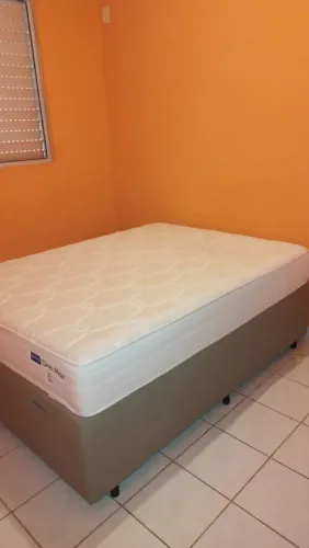 Cama de casal com baú e colchão de molas.
