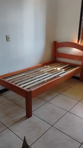Cama solteiro de madeira maciça com colchão.