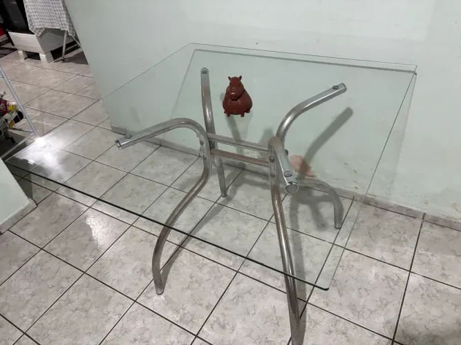 Mesa para quatro lugares com tampo em vidro.