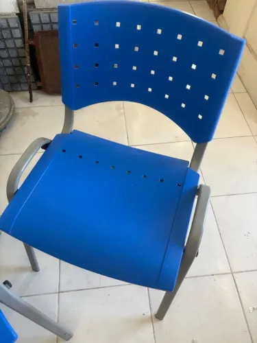 Cadeira fixa empilhável de plástico azul com estrutura de metal cinza