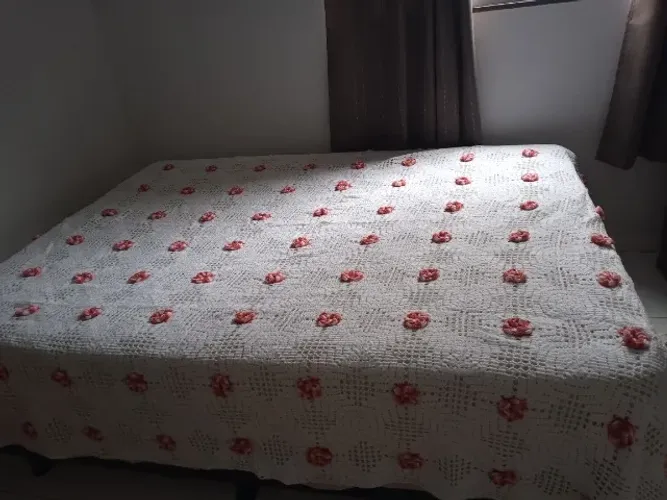 Colcha de crochê branca, com rosas vermelhas.