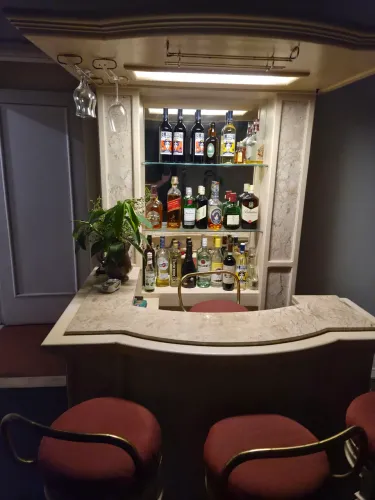 Bar Residencial com Balcão de Mármore, Espelho e Prateleiras de Vidro.