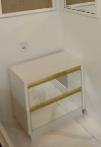 criado-mudo branco com gavetas espelhadas e detalhes dourados