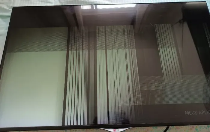 TV LG de 49 polegadas com imagem distorcida e linhas verticais na tela.