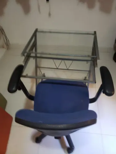Mesa de escritório em vidro e metal com cadeira giratória azul