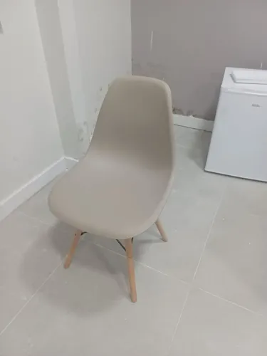 Cadeira estilo Eames com assento cinza e pés de madeira