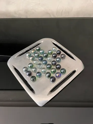 Jogo resta um em alumínio fundido e com bolinhas de gude. 