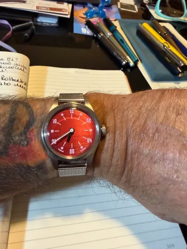Relógio Automático marca Paulin, fundo vermelho e pulseira de aço prata.