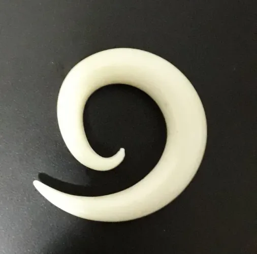 Alargador espiral em acrílico, cor bege, formato caracol.