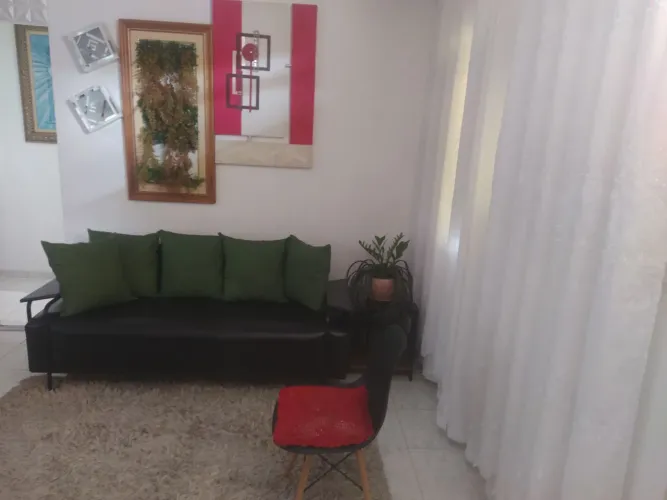 Sofá tapete cortina uma cadeira e uma mesinha lateral