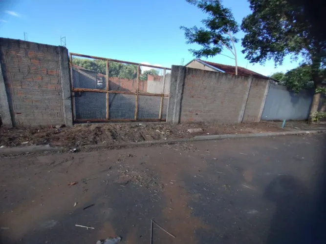 Terreno murado com edicula no asfalto.