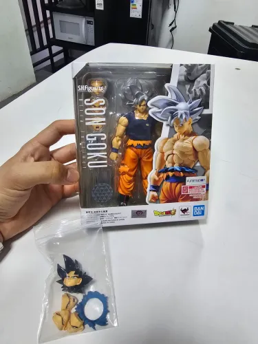 Goku instinto superior Sh figuats Bandai, com camisa de tecido e cabeça com rostos a mais.