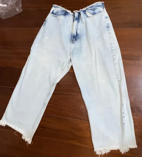 Calça jeans wide leg com lavagem clara estonada e acabamento desfiado