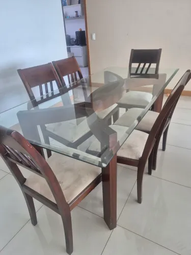 Mesa de vidro e madeira com seis cadeiras.