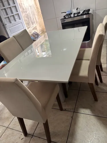 mesa retangular com tampo de vidro e seis cadeiras estofadas em tom bege