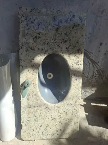 Pia de banheiro de granito Branco Dallas com cuba cerâmica oval instalada.