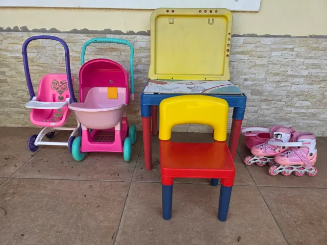 Dois carrinhos de bebê, uma mesinha com cadeirinha e um patins para crianças