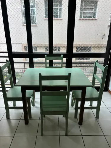 Mesa de madeira estilo retrô com quatro cadeiras.
