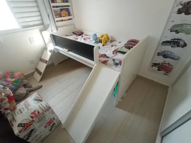 Cama infantil com escorregador e lousa.