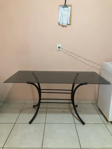 Mesa de jantar com tampo de vidro fumê e base de ferro preta